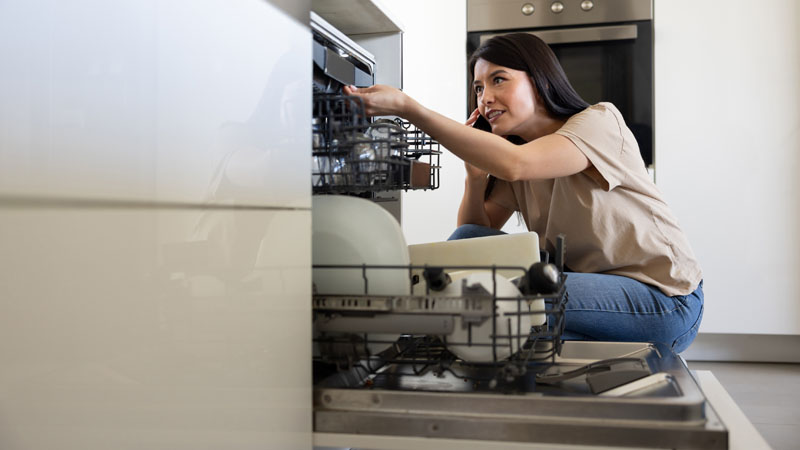 jovem adulta a fazer a manutenção da máquina da loiça 